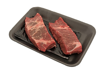 Two raw beef boneless short ribs in a black foam butcher tray isolated on a white background.