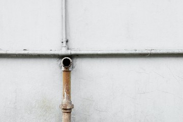 rusted water pipes on cement wall.