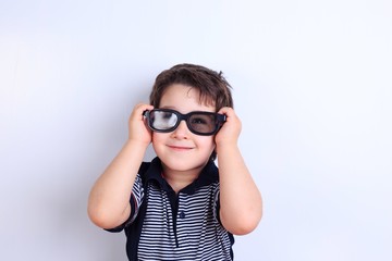 Happy smiling boy looking through sunglasses, studio shoot on white. Children, fashion and lifestyle concept