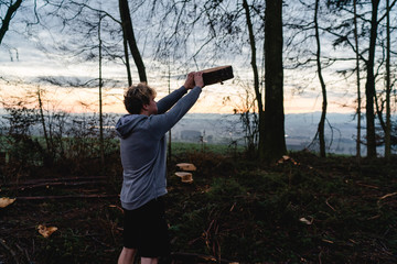 Young man doing workout with some wood in a forrest in Austria