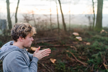 Young man rubbing hands in a forrest in Austria
