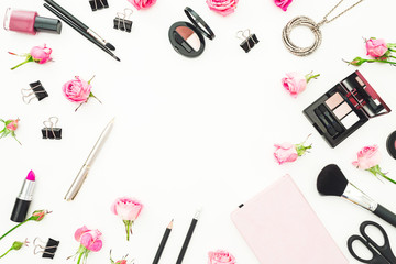 Female workspace with cosmetics, accessories and pink roses on white background. Top view. Flat lay. Beauty frame background.