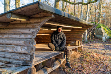 Hiker sitting inside wind shelter enjoying the morning sun on a cold day.