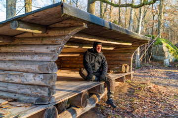 Hiker sitting inside wind shelter enjoying the morning sun on a cold day.
