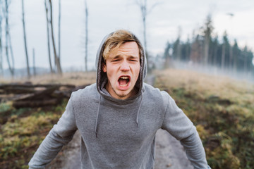 Young man screaming in a forrest in Austria at sunrise