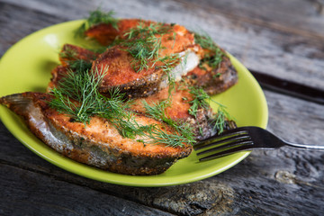 Plate with fried fish on a wooden table