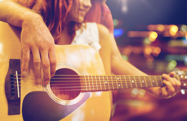 close up of couple with guitar over night lights