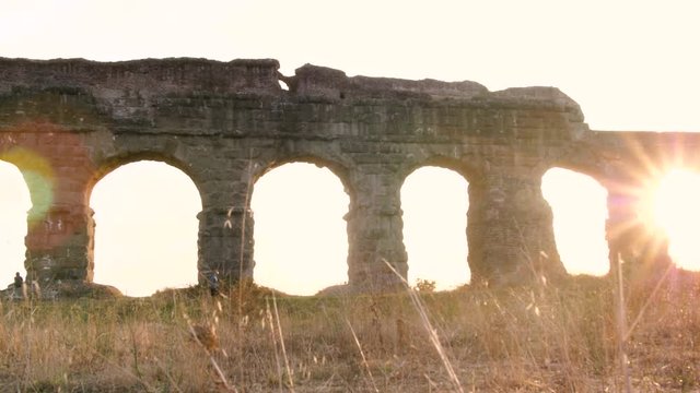 Young man in sportswear running along ancient roman aqueduct Appio Claudio. Training outdoor alone in peaceful park in Rome at sunset slow motion.