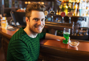 man drinking green beer at bar or pub
