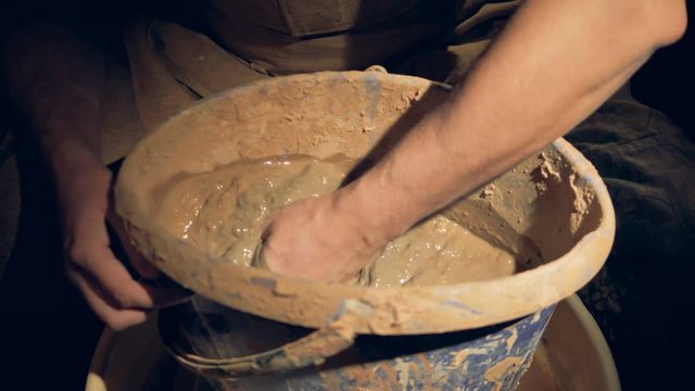 A man potter starts mixing clay in a bucket.