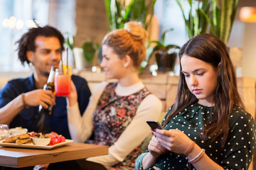 woman with smartphone and friends at restaurant