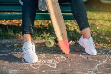 Fototapeta na wymiar Girl on a park bench holding a skateboard.