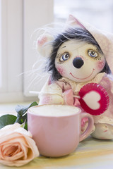 Fototapeta na wymiar A handcrafted toy, a cup of coffe and a rose