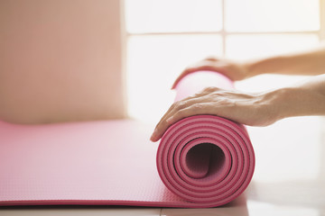 Young woman holding a yoga mat in exercise class for a sport and healthy concept