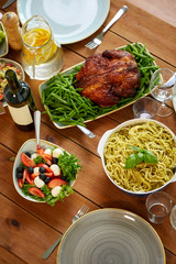 pasta, vegetable salad and roast chicken on table