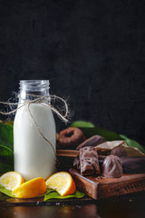 Milk in glass jar with orange and chocolate sweets. Dark wall at background, copy space.