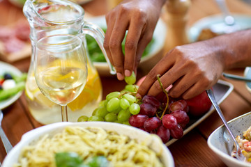 hands taking grape from plate with fruits