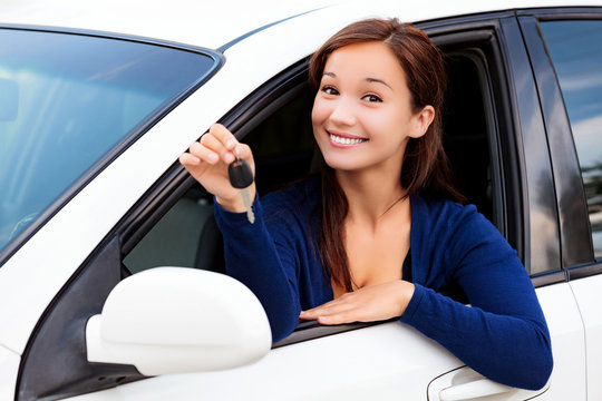 Happy female driver showing car key, cheerful consumer