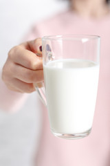 the woman is holding a glass mug of milk