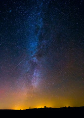 Fototapeta na wymiar Night landscape image with colorful milky way and yellow light in the horizon