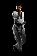 Portrait of an asian professional taekwondo black belt degree (Dan) preparing for fight. Isolated on black background with copyspace