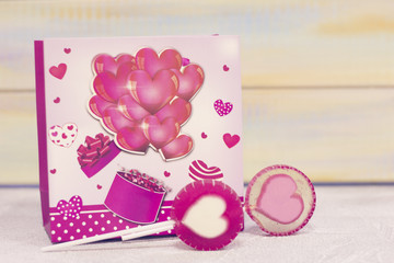 St. Valentine's gifts- a pink package with hearts and two lolipop candies with heart image. St. Valentines, anniversary, wedding concept with copy space.