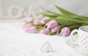Obraz na płótnie Canvas A bouquet of pink tulips and heart shape. The Valentine's Day concept, wedding, engagement and other romantic events. Top view, close-up, vintage white background