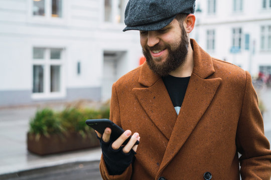Smiling man using smartphone on street