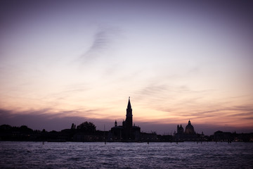 Fototapeta na wymiar Italian silhouette of Venice sunset, City panorama shot from sea, Italian city panorama vintage shot from sea and sky, Sunset in Venice background, Dark scene of Venice, Symbol of evening Venice