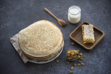 pancakes, honey and raisins on a dark background