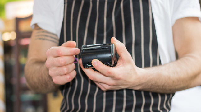 Man is working with a debit card reader. It's faster and popular way to pay a bill by hand swiping credit card in restaurant, cafe or store today. Concept: demonetization & technology. 