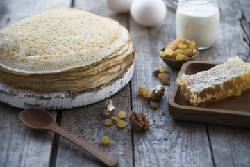 pancakes, honey and raisins on a wooden table