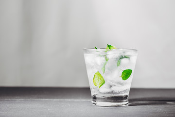 Mojito cocktail with lime and mint in glass on a grey stone background