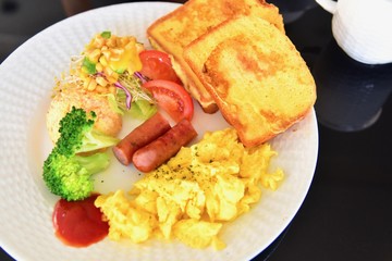 Typical European Breakfast Consisting of Salad, Scrambled Eggs, French Toasts, and Sausages