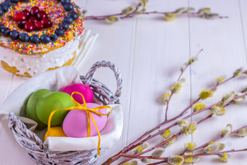 Easter composition with decorated cake and colored eggs on  white wooden background