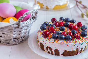 Easter composition with decorated cake and colored eggs on  white wooden background