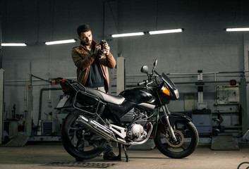 Plakat Young man in leather jacket standing near motorcycle in garage
