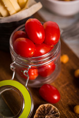 Red tomatoes in glass jar on wooden board