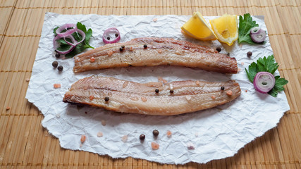 Appetizing salted herring fillet on a bamboo napkin.
