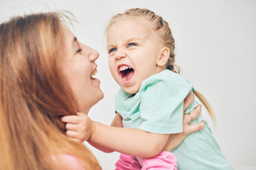 Young mother and her daughter playing in the bedroom