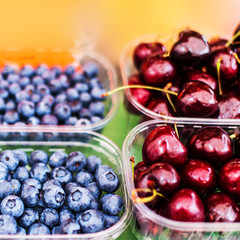  Healthy local food  concept  with assorted berries on display at farmers market, macro.