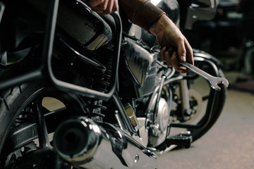 Fototapeta na wymiar Biker's hands holding wrench near motorcycle