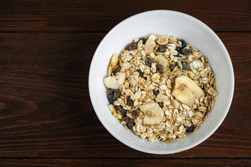 Top view of cereal breakfast with dried banana and raisins. Healthy vegetarian snack.