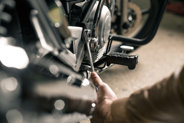 Biker's hands holding wrench near motorcycle