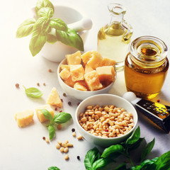Ingredients for homemade pesto - basil, lemon, parmesan, pine nuts, garlic, olive oil and salt on white concrete background. Top view, flat lay, copyspace. Square crop