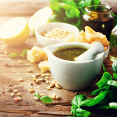 Ingredients for homemade pesto - basil, lemon, parmesan, pine nuts, garlic, olive oil and salt on rustic wooden background. Top view, flat lay, copyspace. Banner. Square crop