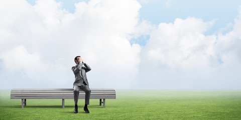 Young man in summer park on bench do not want to see anything