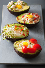 eggs baked in avocado with bacon, cheese, tomato and alfalfa sprouts
