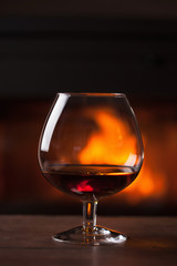 a glass of cognac in front of fireplace