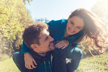 Beautiful couple of lovers joking outdoors in the park and enjoying their time together , with...